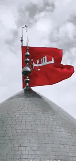 Vibrant red flag atop a grey dome against a cloudy sky.