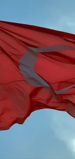 Red flag waving against a bright blue sky.