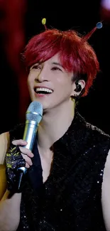 Singer with red hair holding a microphone, smiling on stage.