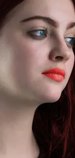 Portrait of a person with red hair and vibrant red lipstick, set against a red background.