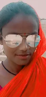 Woman in red sari with reflective sunglasses.