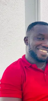 Smiling man in red shirt with a bright, neutral background.