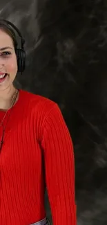 Woman in vibrant red sweater with headphones on dark background wallpaper.