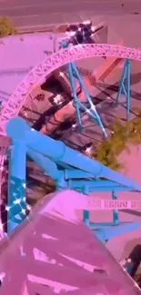 Aerial view of pink and blue roller coaster in amusement park.