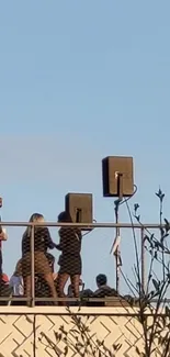 Rooftop gathering with clear blue sky background and industrial railing.