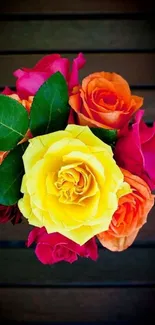 Vibrant bouquet of roses with yellow, orange, and pink blooms on a dark background.