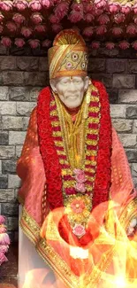 Sai Baba statue with red garland and pink flowers on a stone background.