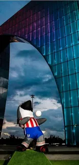 Colorful shark mascot in front of an illuminated modern arch at night.