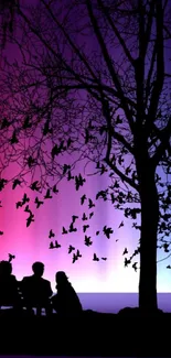 Silhouette of a tree and birds against a vibrant purple gradient sky.