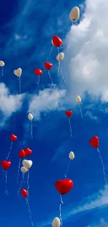 Blue sky with red and white balloons floating among clouds.
