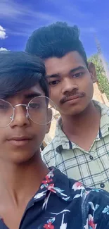 Young friends take a selfie with a bright blue sky in the background.