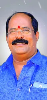 Smiling man in blue shirt with a soft gradient backdrop.