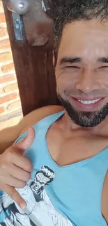 Smiling man in blue tank top with thumbs up gesture.