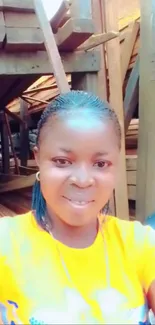 Smiling person in orange shirt with wood backdrop.