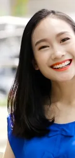 Smiling woman in a vibrant blue top enjoying a sunny day.