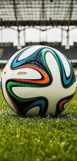 Colorful soccer ball on a grassy field in an empty stadium.