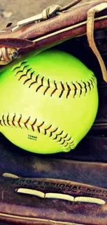 Bright green softball in a brown leather glove on a mobile wallpaper.