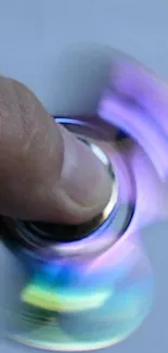 Purple and blue fidget spinner in motion against a blurred background.