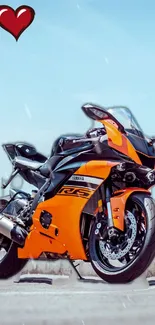 Orange sports bike with heart icon against clear sky.