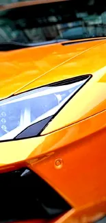 Close-up of a vibrant orange sports car headlight and sleek design.