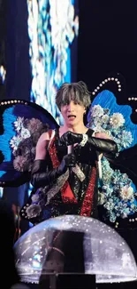 Performer in vibrant butterfly costume with floral accents on stage.