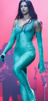 Woman in teal outfit performing on stage with colorful lights.