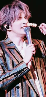 Performer singing on stage with microphone and colorful jacket.