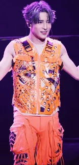 Dynamic stage performer in bright orange outfit on a vivid mobile wallpaper.