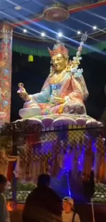 Vibrant religious statue illuminated at night with cultural patterns.