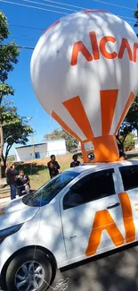 A unique car with balloon decor on a sunny street, vibrant and eye-catching.