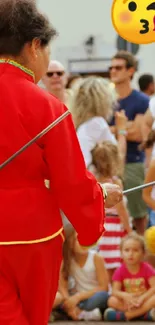 Performer in red captivates a lively crowd during an outdoor event.