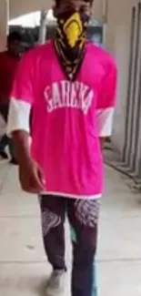 Fashion-forward individual in vibrant pink streetwear with a unique mask.