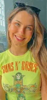 Woman wearing a lime green graphic tee, smiling outdoors.