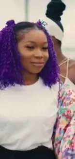 Woman with vibrant purple curly hair in outdoor setting.