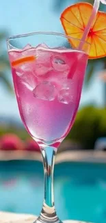 Pink cocktail by the pool with orange slice.