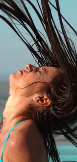 Woman flipping hair at the poolside with a vibrant turquoise background.