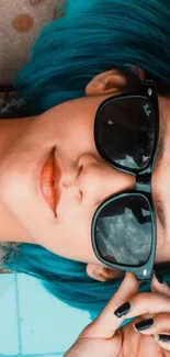 Girl with blue hair and sunglasses lying relaxed.