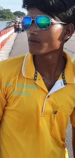 Person wearing reflective sunglasses and yellow shirt.