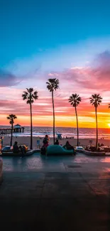 A vibrant sunset over a beach with palm trees and a colorful sky.