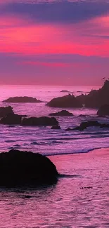 Vibrant sunset over rocky beach with pink and purple hues.