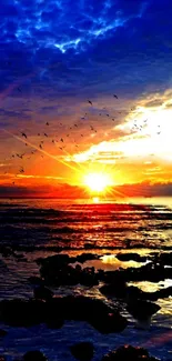 Vibrant sunset over ocean with colorful sky and birds in view.