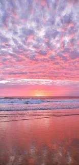 Vibrant pink and purple sunset over ocean waves on a serene beach.