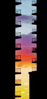 Silhouetted buildings against vibrant sunset gradient sky.