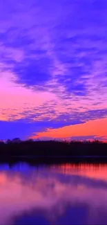 Vibrant sunset over lake with purple sky reflecting in calm waters.