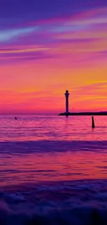 Vibrant sunset with lighthouse over ocean.