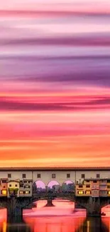 Sunset over a historic bridge with pink and purple sky reflections.