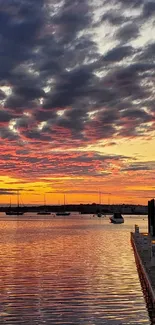 Sunset over harbor with vibrant colors reflecting on water.