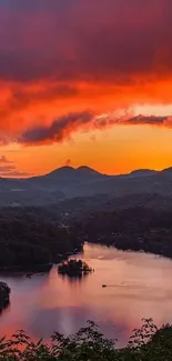 A vibrant sunset over mountains and a lake, with glowing orange skies.