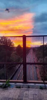 Sunset over railway track with vibrant sky.