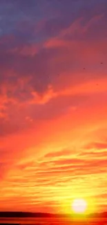 A vibrant orange sunset over a peaceful lake with a colorful sky.